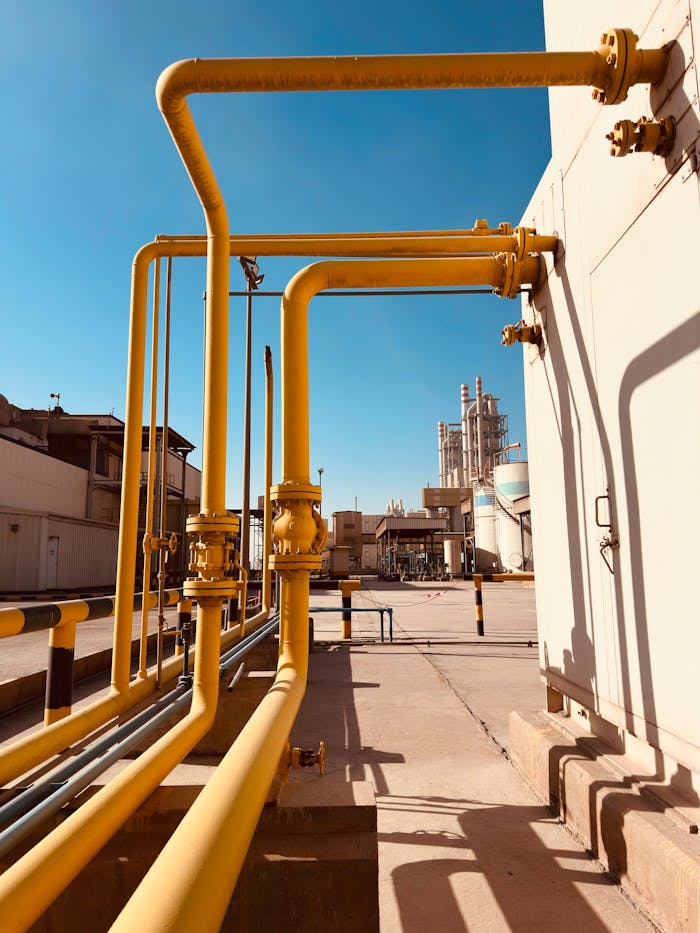 Yellow gas pipeline with clear blue sky at a Saudi cement factory.